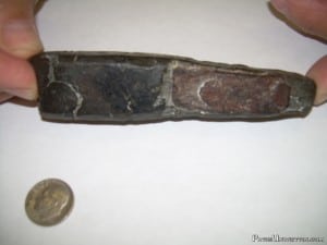 Tool fragment with inlaid metal, possibly rivets.